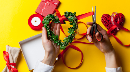 Female hands are holding a green heart shape gift before wrapping