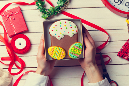 Female hands are holding Easter gingerbread cookie before wrappingの写真素材