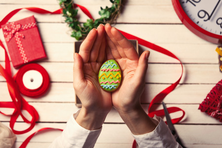 Female hands are holding Easter gingerbread cookie before wrappingの写真素材