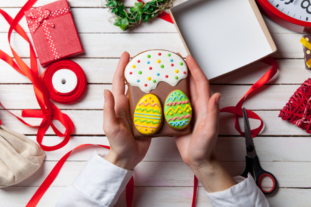 Female hands are holding Easter gingerbread cookie before wrappingの写真素材