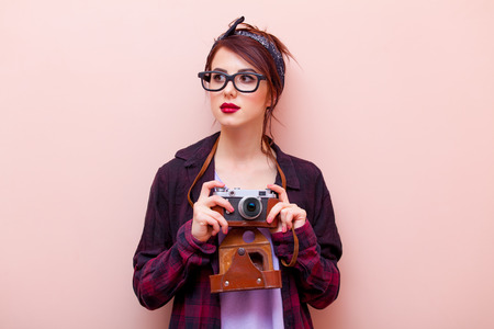 portrait of beautiful young woman with camera standing on the pink backgroundの写真素材