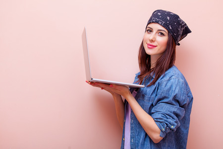 portrait of beautiful young woman with laptop standing on the pink backgroundの写真素材