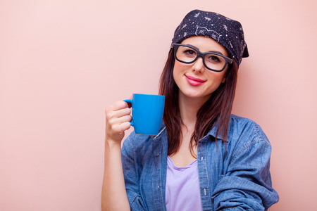 portrait of beautiful young woman with blue cup standing on the pink backgroundの写真素材