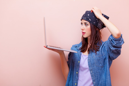 portrait of beautiful young woman with laptop standing on the pink backgroundの写真素材