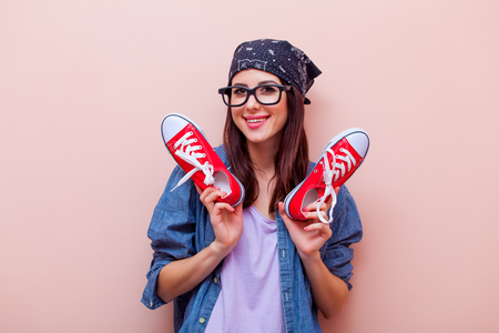 portrait of beautiful young woman with red gumshoes standing on the pink backgroundの写真素材
