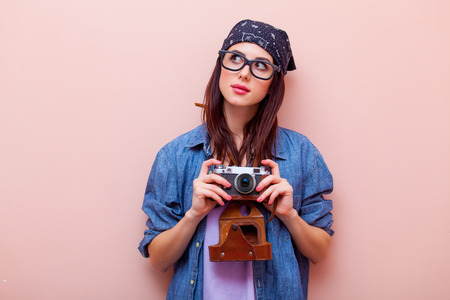 portrait of beautiful young woman with camera standing on the pink backgroundの写真素材