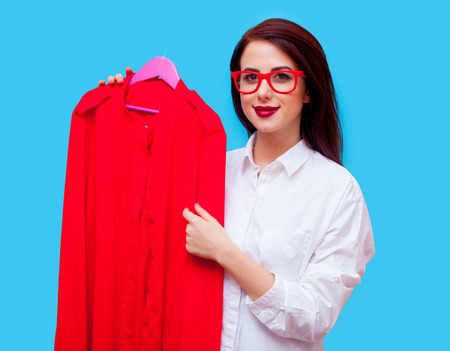 portrait of beautiful young woman in glasses with dress standing on the blue backgroundの写真素材