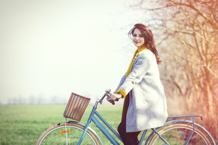 portrait of beautiful young woman on blue bicycle near treeの写真素材