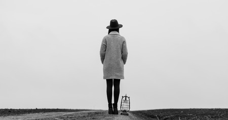 portrait of a young beautiful woman with lantern standing on the roadの写真素材