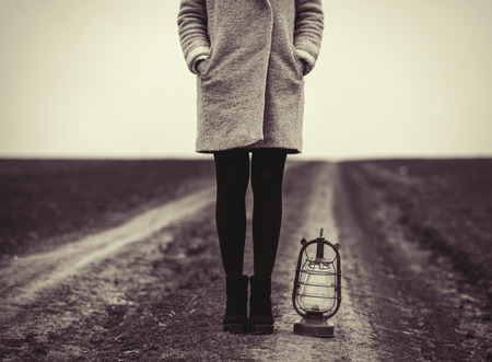 photo of young woman with lantern standing on the roadの写真素材