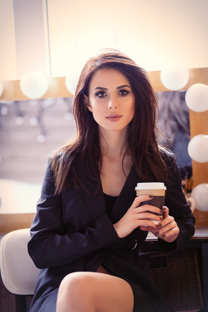 portrait of young beautiful woman with cup of coffee sitting on the chairの写真素材