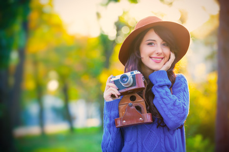 portrait of the beautiful young woman with camera in the parkの写真素材