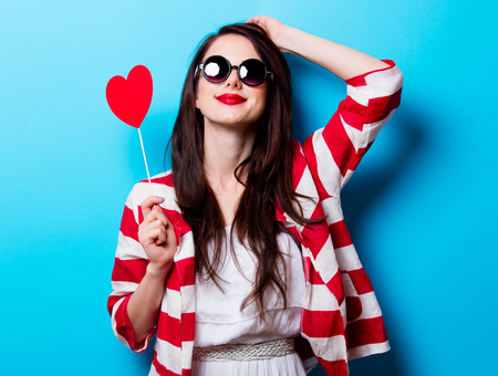 portrait of the beautiful young woman  with heart shaped toy on the blue backgroundの写真素材