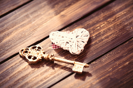 white heart shaped toy and golden key on the brown wooden tableの写真素材
