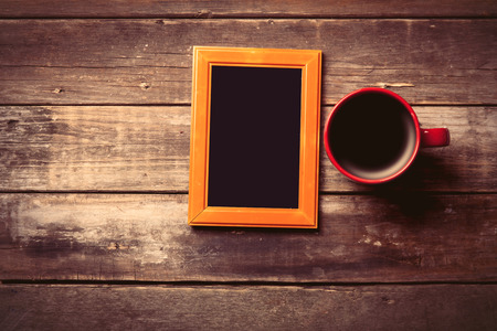 photo frame and cup of coffee on the brown wooden backgroundの写真素材