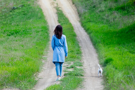 photo of the beautiful young woman with dog walking on the roadの写真素材