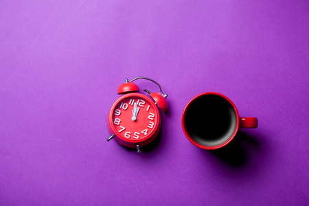 photo of the cup of coffee and clock on the purple backgroundの写真素材