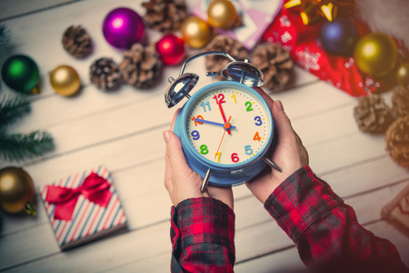 photo of the child hands holding a blue clock on the christmas decorations backgroundの写真素材