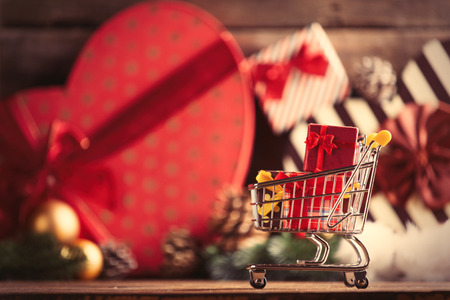 photo of the cart for shopping with gifts on the christmas decorations backgroundの写真素材