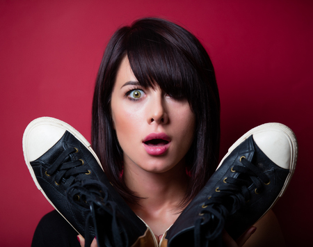 portrait of the beautiful young woman with gumshoes on the vinous backgroundの写真素材