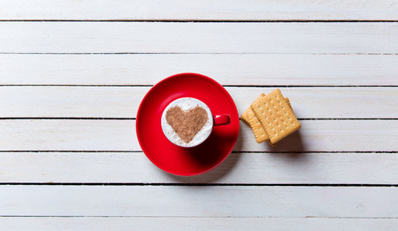 photo of the cup of coffee and cookies on the white wooden background