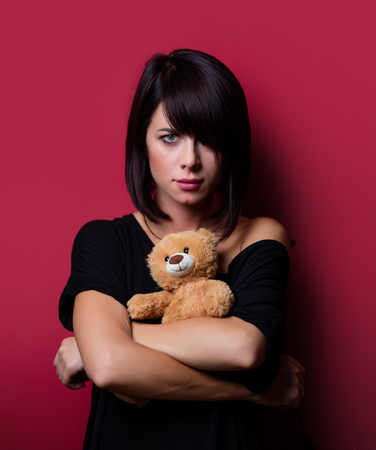 portrait of the beautiful young woman with teddy bear on the vinous backgroundの写真素材