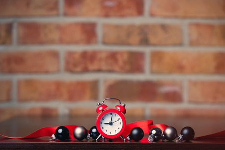 Red alarm clock and christmas baubles with other on brick wall backgroundの写真素材