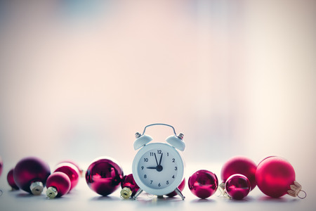 Christmas toys baubles and retro alarm clock on white bokeh background