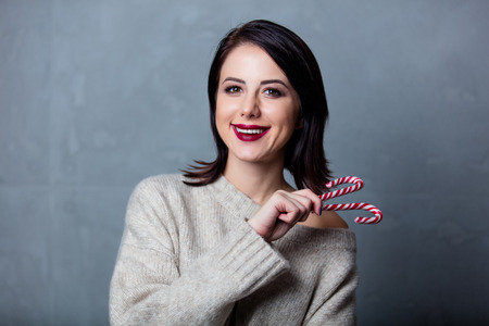 Portrait of a style brunette woman with christmas lollipop on grey backgroundの写真素材