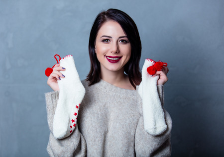 Portrait of a style brunette woman with christmas socks on grey backgroundの写真素材