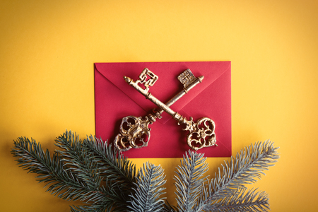 Red christmas envelope near a pine branch and keys on yellow backgroundの写真素材