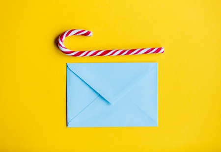 Blue christmas envelope and lolipop on yellow backgroundの写真素材