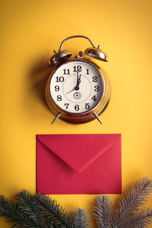 Red christmas envelope and little alarm clock on yellow backgroundの写真素材