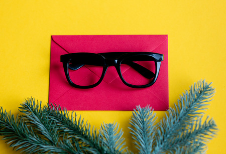 Red christmas envelope and style glasses on yellow backgroundの写真素材