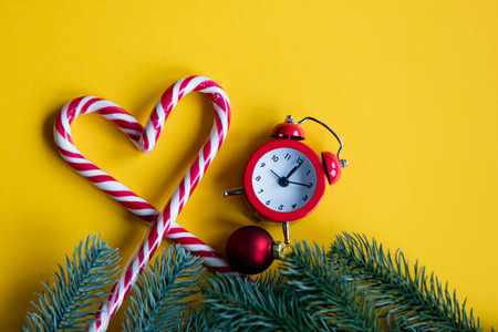 christmas alarm clock  and lolipop on yellow backgroundの写真素材