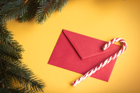 Red christmas envelope and lolipop on yellow backgroundの写真素材
