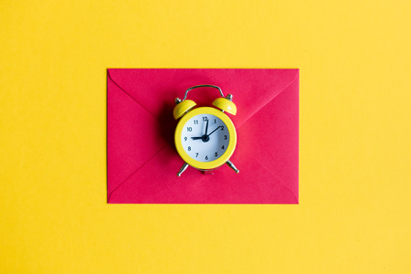 Christmas alarm clock and red envelope on yellow backgroundの写真素材