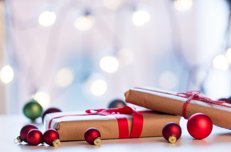 Christmas gift and baubles around it on fairy lights background