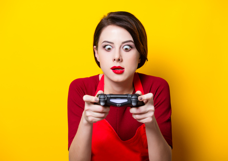 WROCLAW, POLAND - 20 december 2017: Young housewife with PlayStation 4 joystick on yellow background, Wroclaw, Polandの写真素材