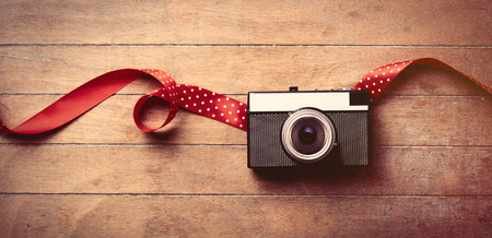 cool retro camera and beautiful red ribbon on the wonderful brown wooden background