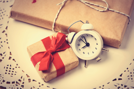 beautiful gifts and alarm clock on white napkin on the wonderful brown wooden backgroundの写真素材