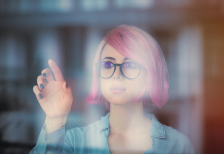 beautiful young woman looking at her reflection in the window and touching itの写真素材