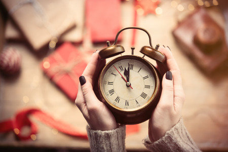 beautiful woman hands holding big golden alarm clock on the wonderful  decoration backgroundの写真素材