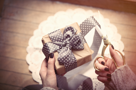 beautiful woman hands wrapping cute gift on the wonderful brown wooden backgroundの写真素材