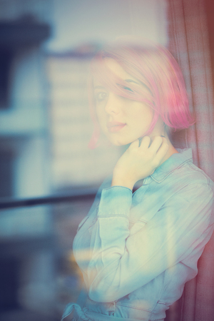 beautiful young woman looking at the window and thinking