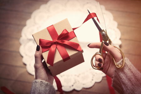 beautiful woman hands wrapping cute gift on the wonderful brown wooden backgroundの写真素材