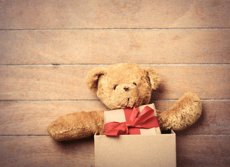 cute teddy bear and small gift in the box on the wonderful brown wooden backgroundの写真素材