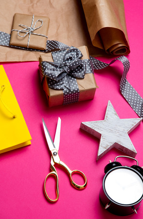 cute gifts, star shaped toy, shopping bag, alarm clock and things for wrapping on the wonderful pink backgroundの写真素材