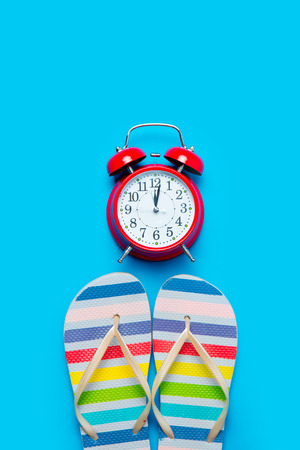 colorful sandals and beautiful alarm clock on the wonderful blue background
