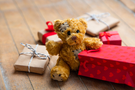 cute gifts, teddy bear and cool red shopping bag on the wonderful brown wooden backgroundの写真素材